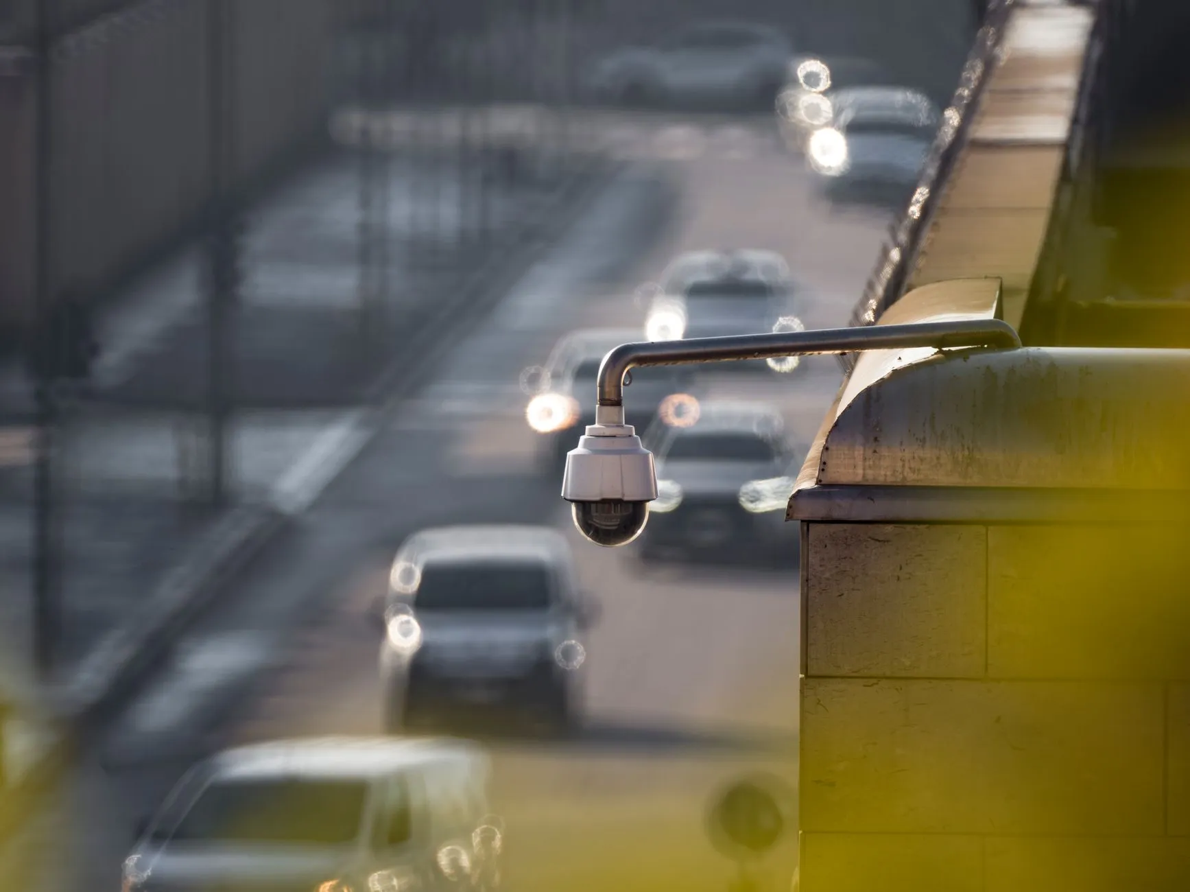 Kamera monitoringu zamontowana na budynku nad ulicą z jadącymi samochodami