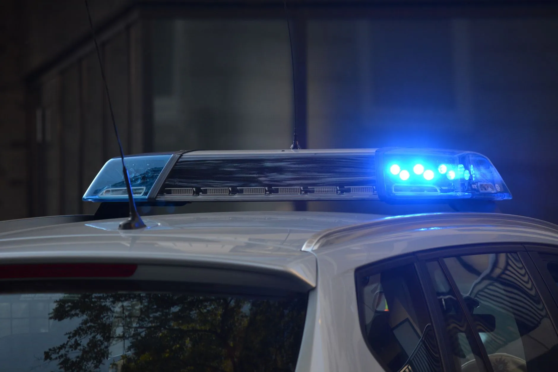 Włączone niebieskie światła ostrzegawcze na dachu radiowozu na tle budynku