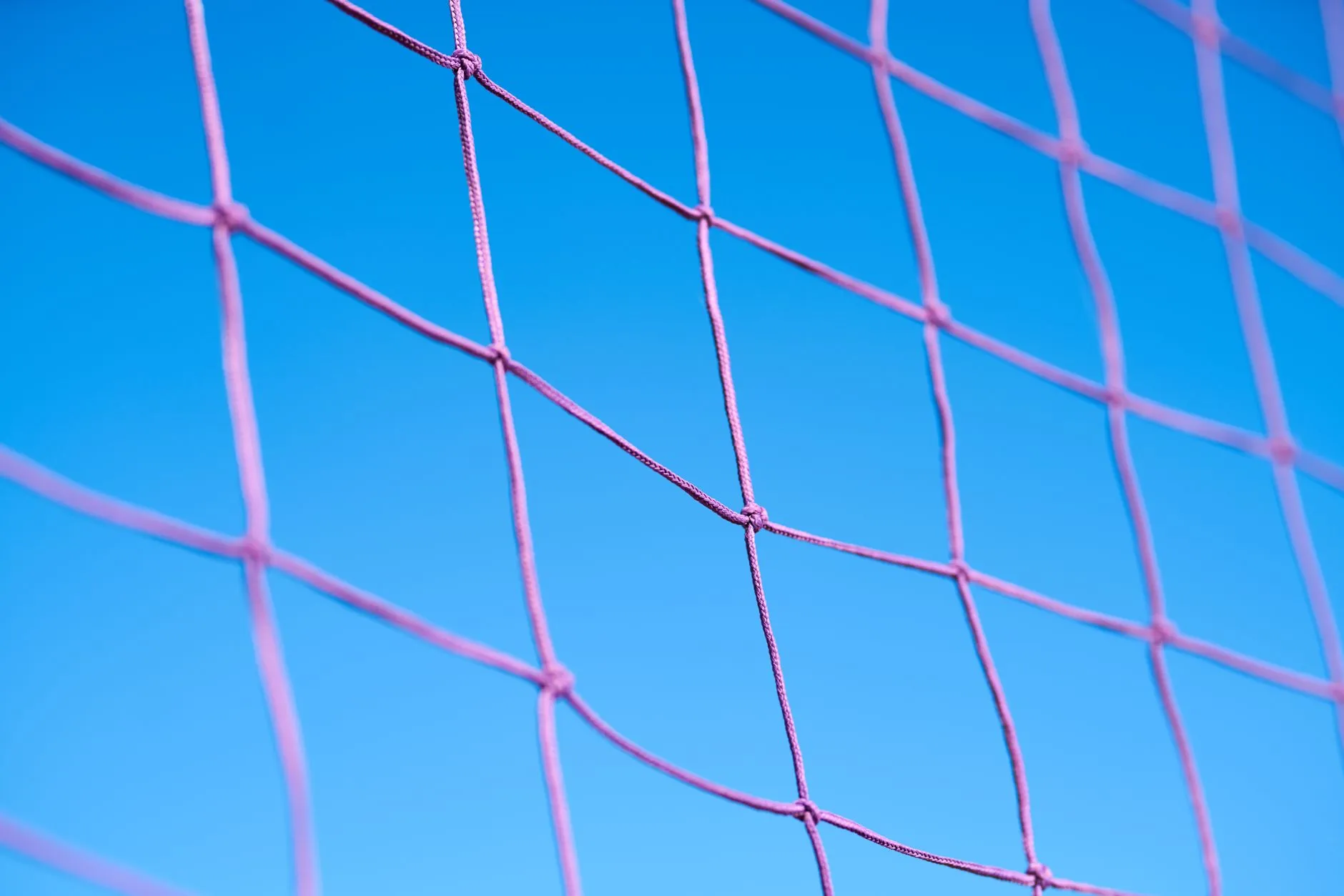Zbliżenie fioletowej siatki siatkarskiej na tle błękitnego nieba