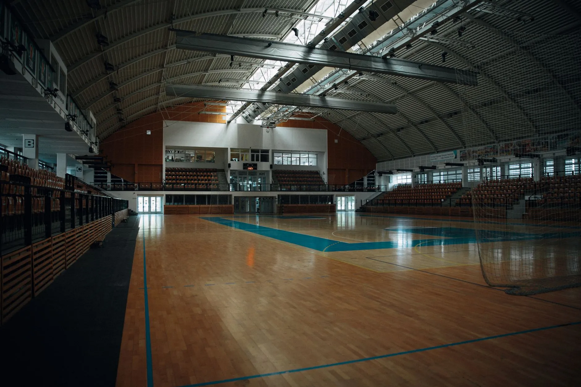 Pusta hala sportowa z drewnianym parkietem i trybunami