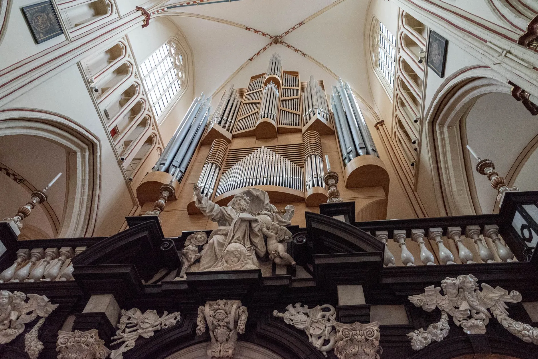 Okazałe organy piszczałkowe nad ozdobną balustradą z rzeźbami we wnętrzu kościoła