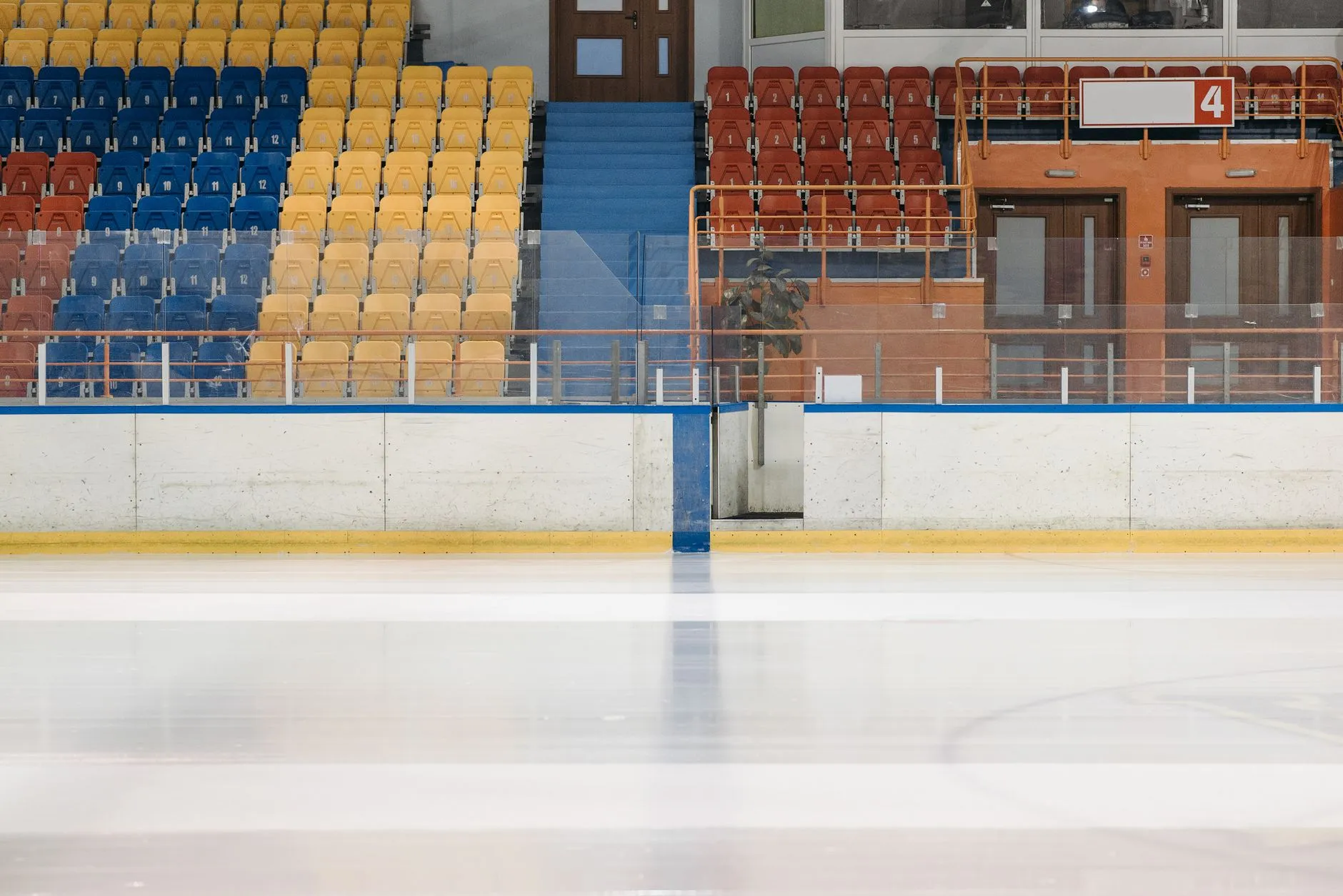 Puste lodowisko z bandami i kolorowymi trybunami w hali sportowej