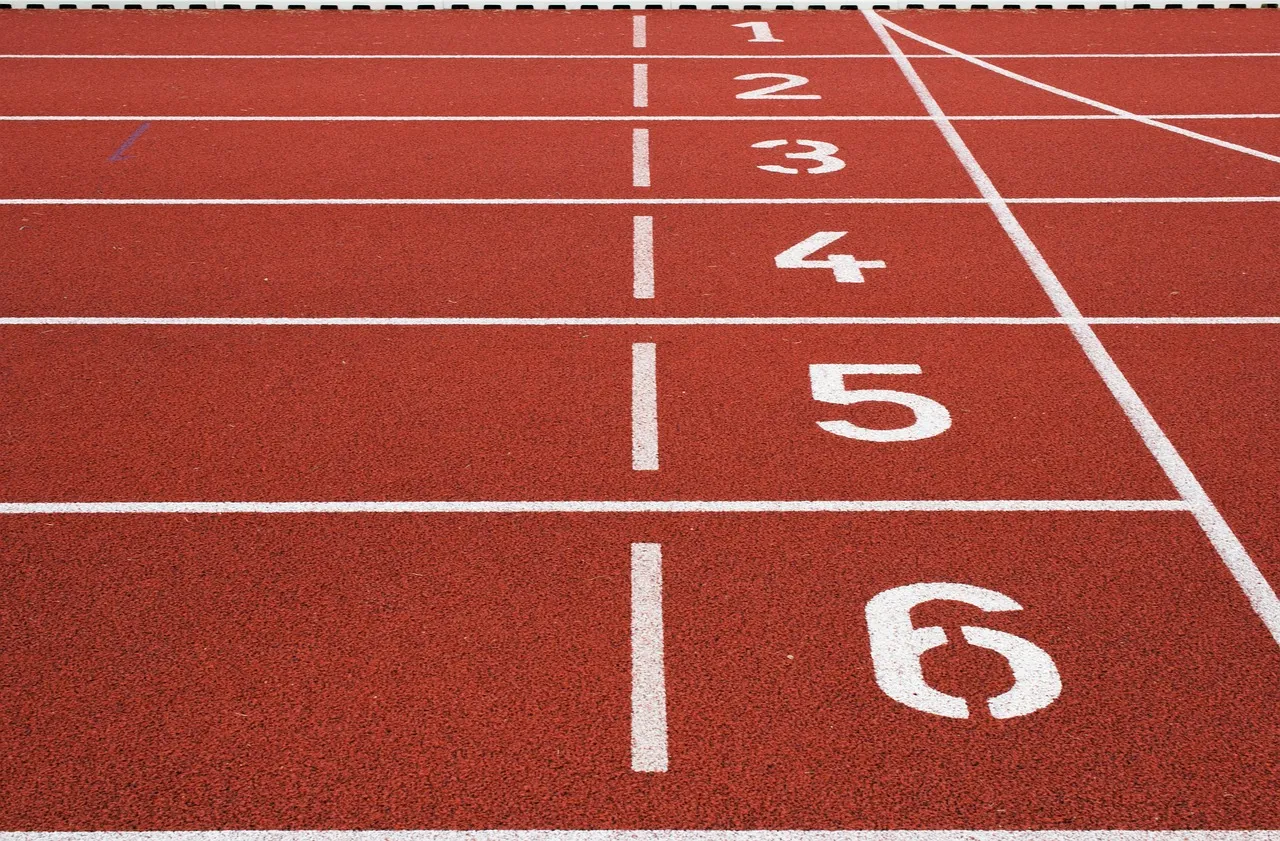 Czerwona bieżnia lekkoatletyczna z białymi liniami i numerami torów od jeden do sześć