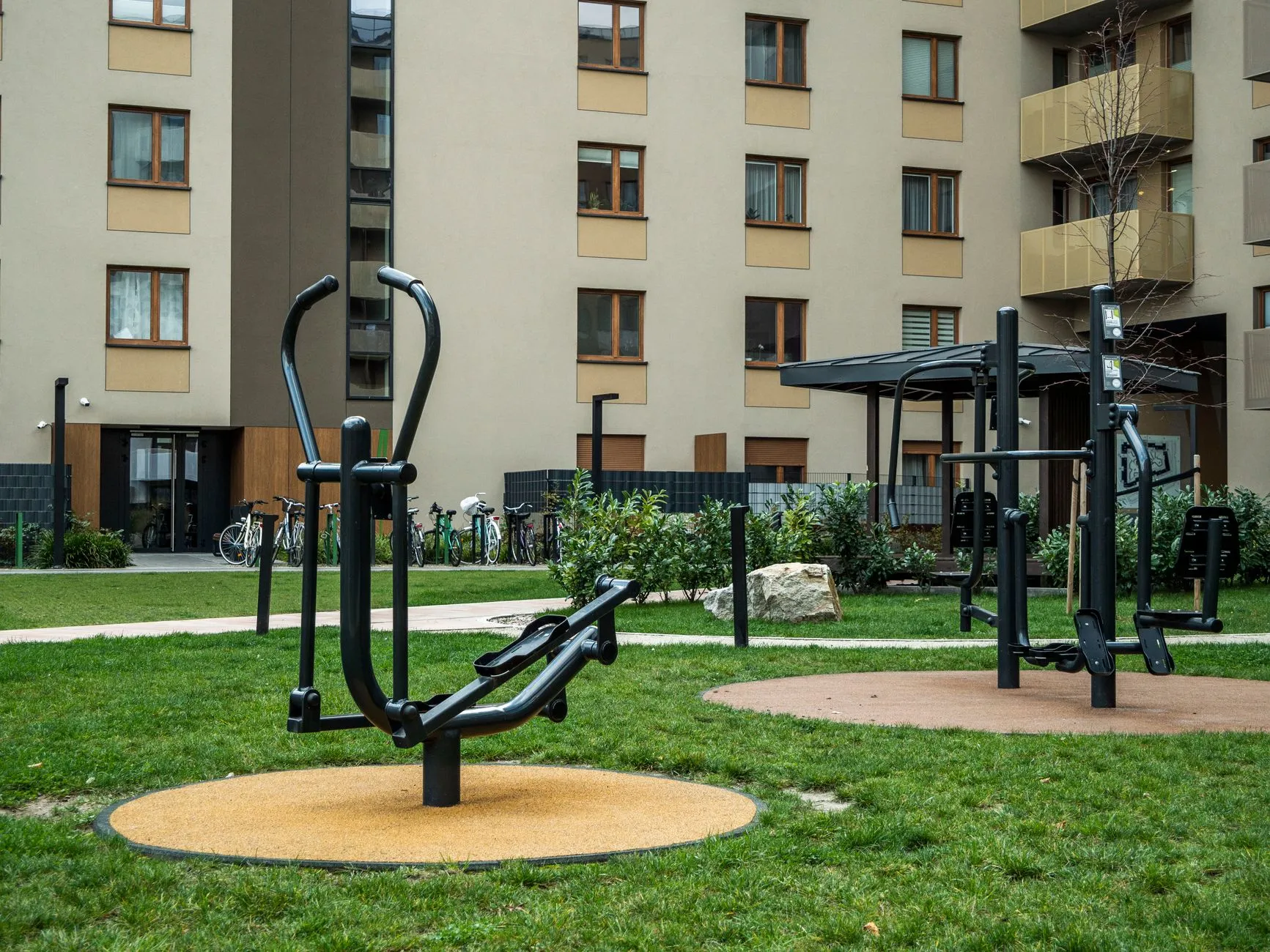 Urządzenia siłowni plenerowej na zielonym dziedzińcu między budynkami mieszkalnymi