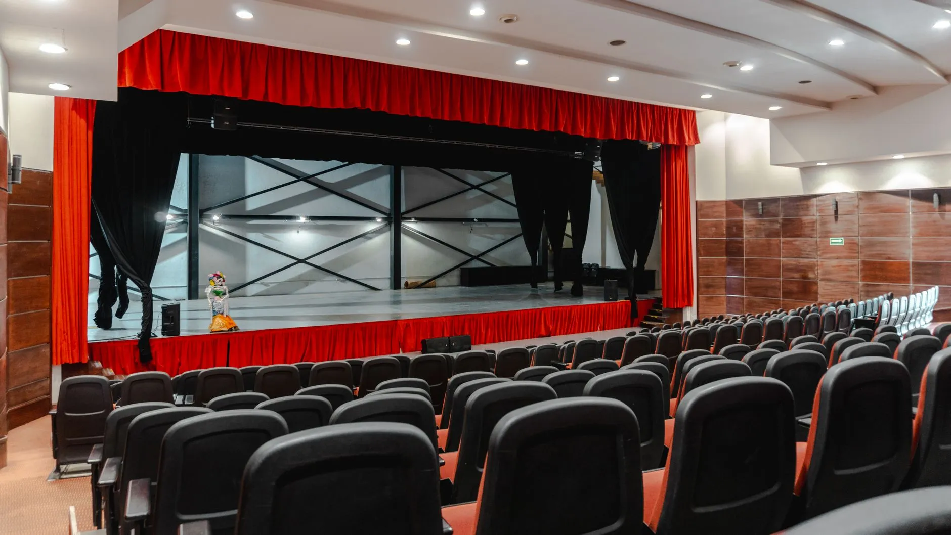 Pusta widownia teatralna z rzędami foteli i sceną otoczoną czerwonymi kurtynami