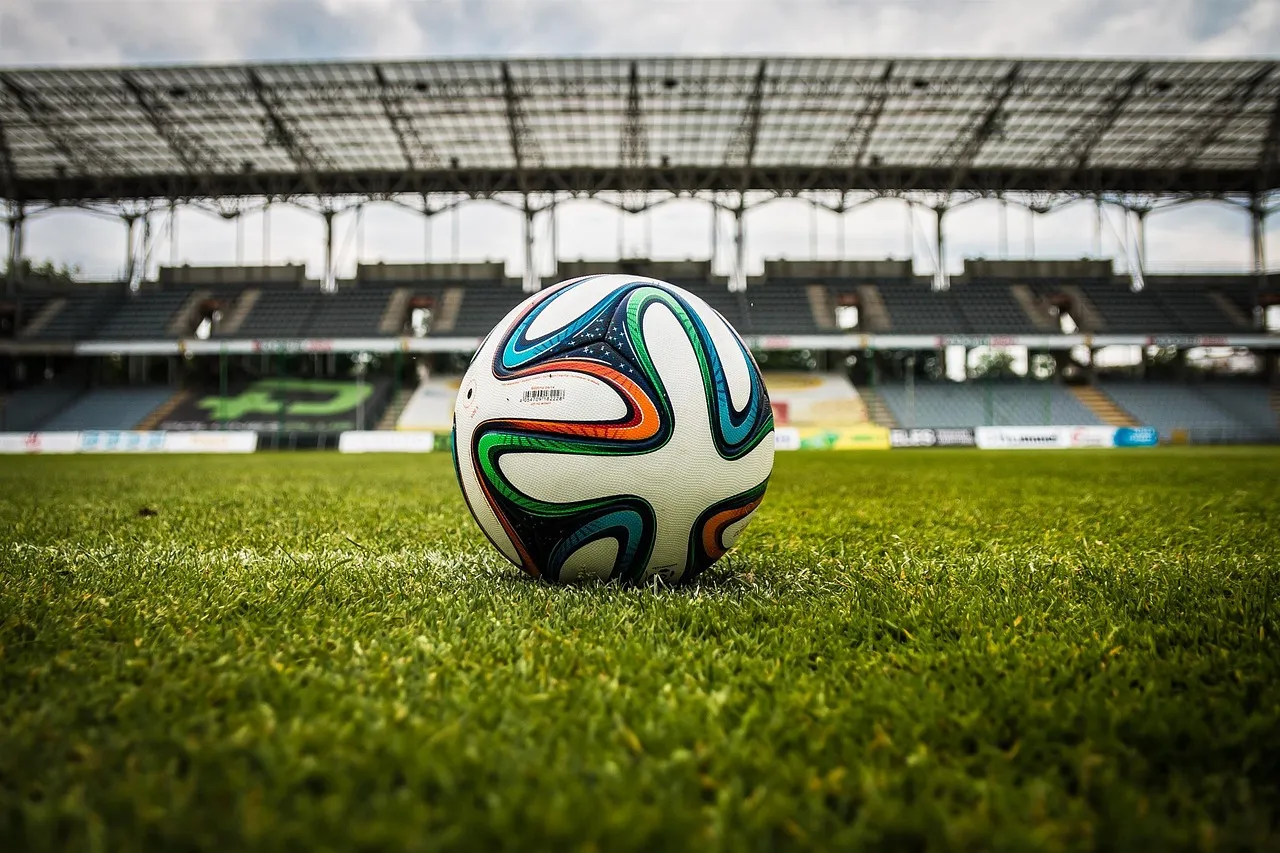 Piłka nożna na zielonej murawie na tle pustych trybun stadionu