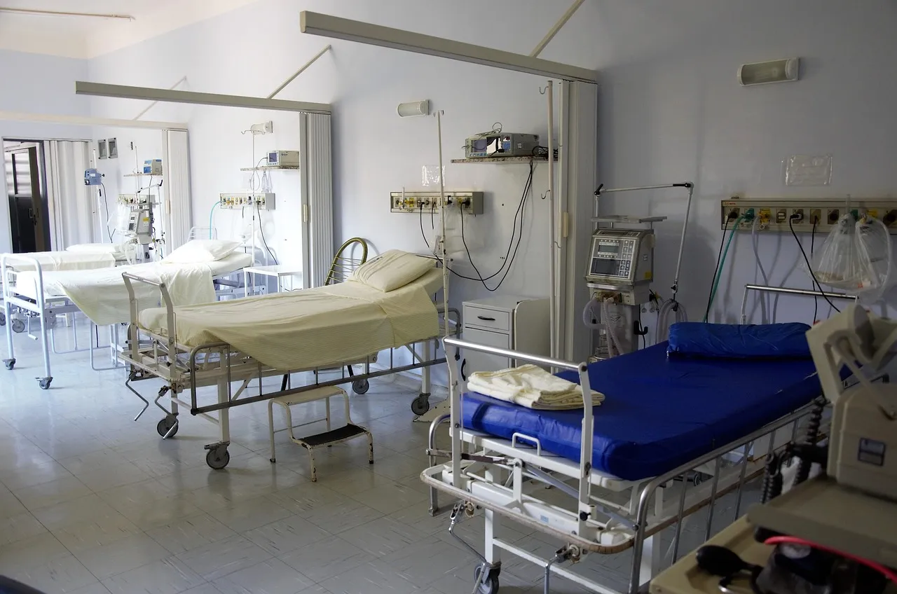Łóżka szpitalne i aparatura medyczna w wielostanowiskowej sali szpitalnej