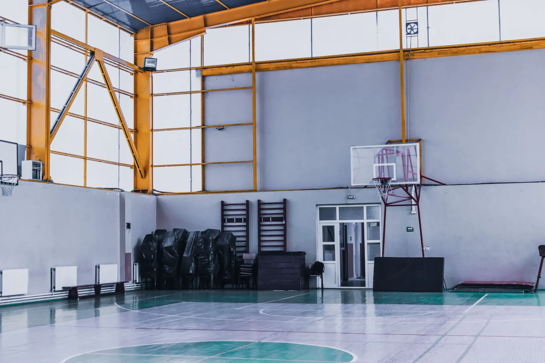 Pusta sala sportowa z koszami do koszykówki, drabinkami i liniami boiska