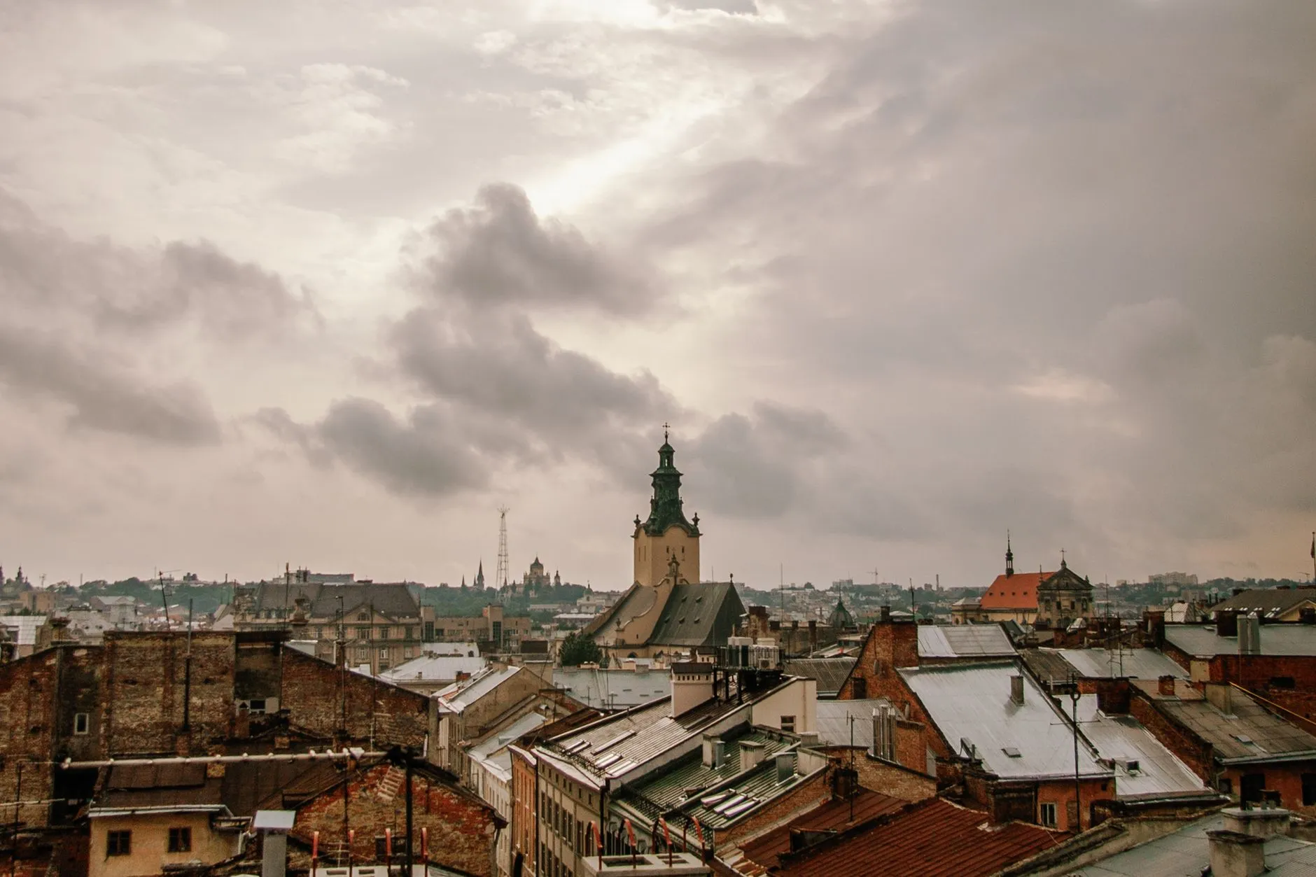 Dachy zabytkowych budynków i wieże kościołów we Lwowie pod zachmurzonym niebem