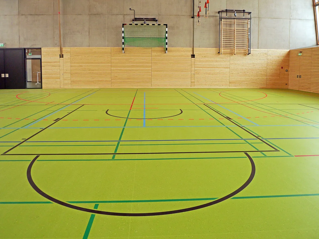 Pusta hala sportowa z liniami boisk i podwieszoną bramką do piłki ręcznej