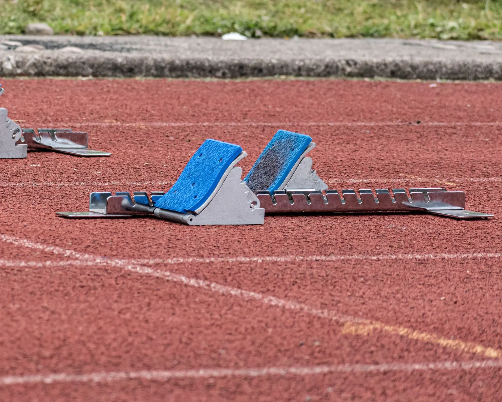 Niebieskie bloki startowe na czerwonej bieżni lekkoatletycznej