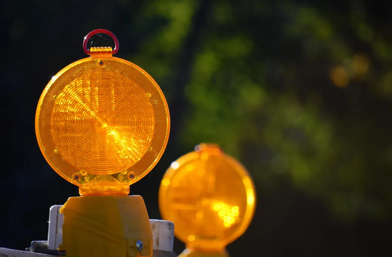 Pomarańczowe lampy ostrzegawcze na barierze zabezpieczającej roboty drogowe