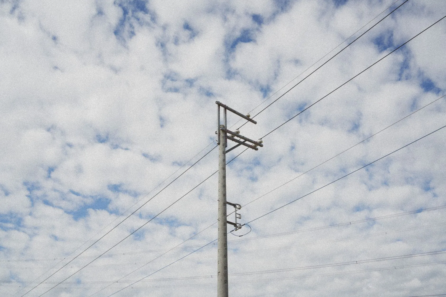 Betonowy słup energetyczny z przewodami na tle zachmurzonego nieba