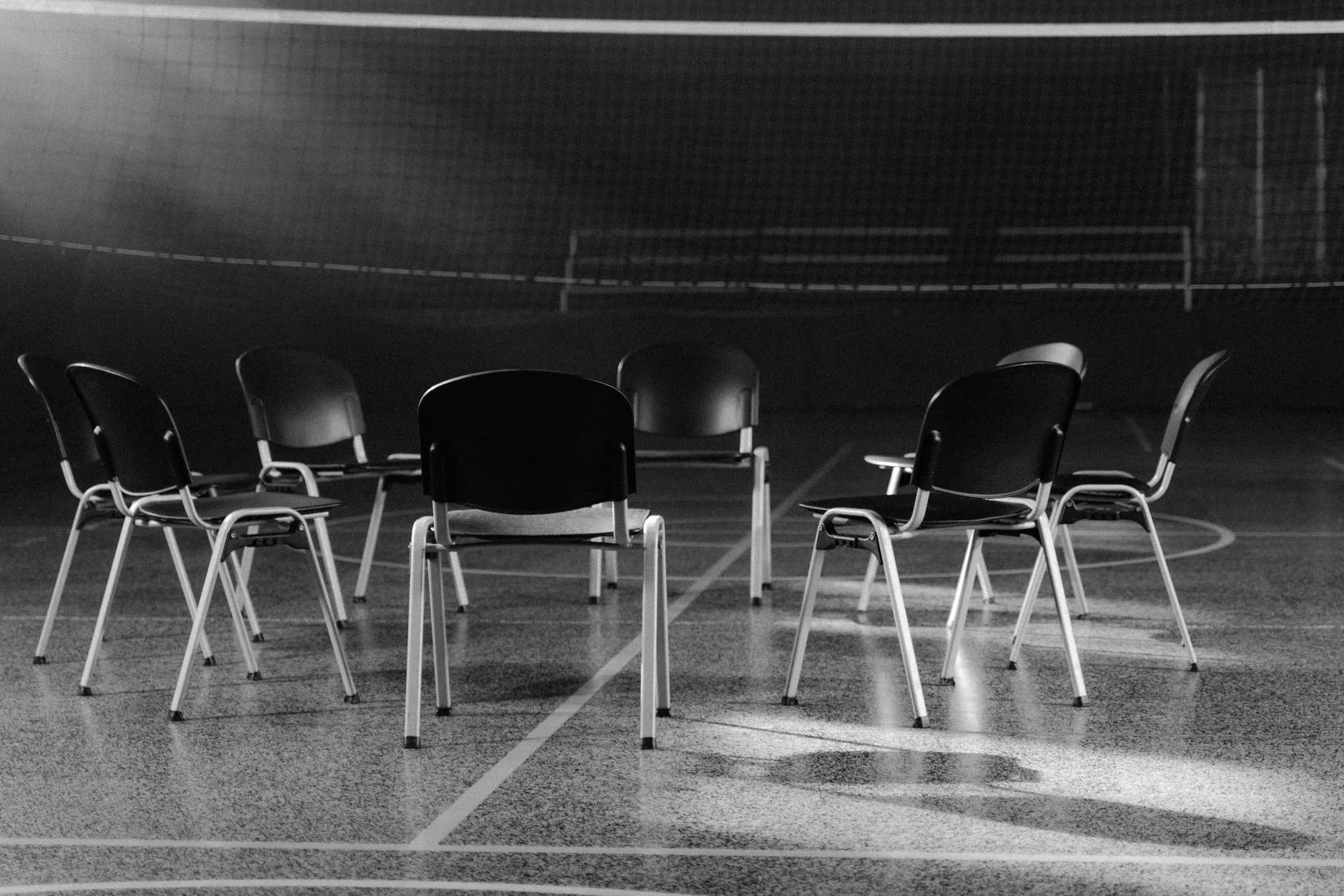 Puste krzesła ustawione w kręgu na boisku wewnątrz sali sportowej